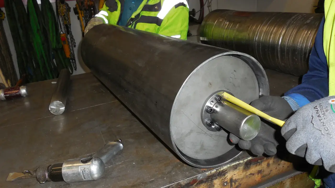 Zwei Mitarbeiter der Korzenski Service GmbH vermessen eine ausgebaute F&ouml;rdertrommel in der eigenen Werkstatt